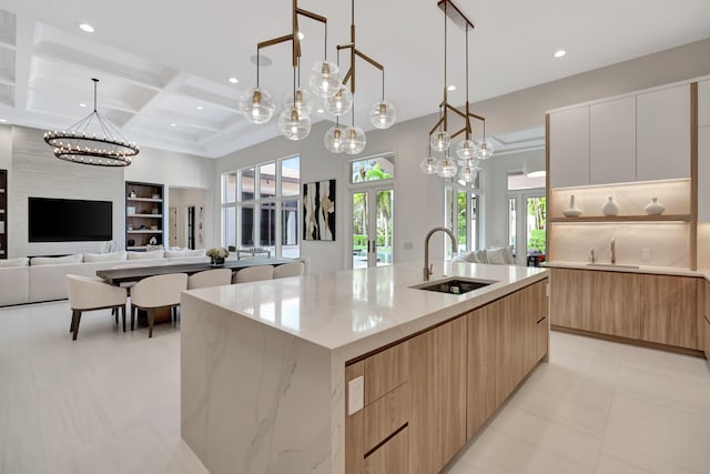 kitchen with sink, a spacious island, white cabinetry, coffered ceiling, and pendant lighting