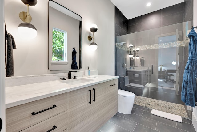 bathroom featuring toilet, vanity, a tile shower, and tile patterned floors