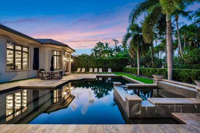 pool at dusk featuring a patio