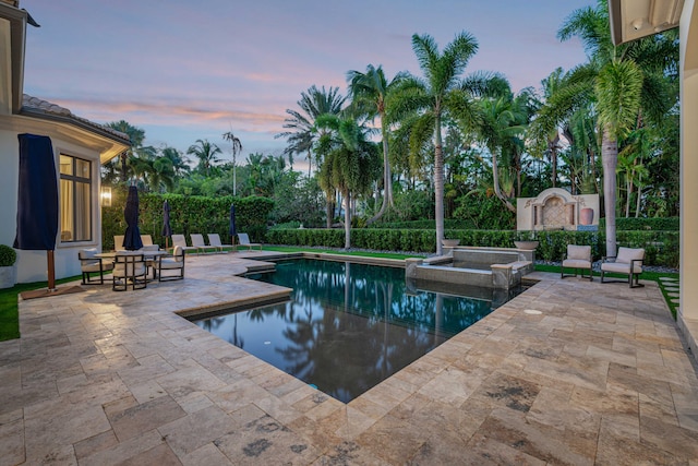 pool at dusk featuring a patio area