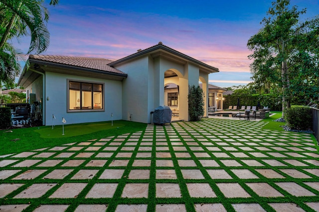 back house at dusk featuring a patio