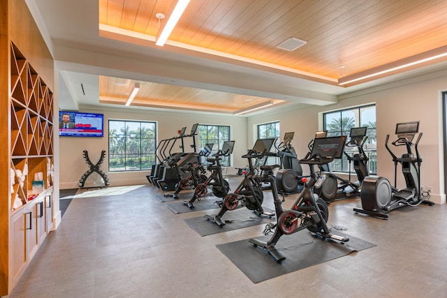 exercise room with wooden ceiling, a healthy amount of sunlight, and a raised ceiling