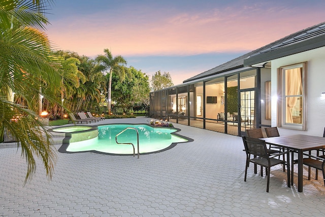 pool at dusk with an in ground hot tub and a patio