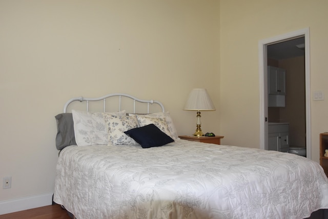 bedroom featuring ensuite bathroom and dark hardwood / wood-style floors