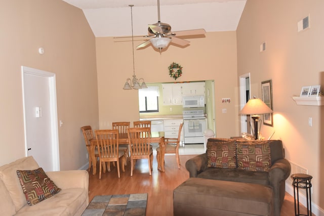 living room with high vaulted ceiling, light wood-type flooring, and ceiling fan with notable chandelier