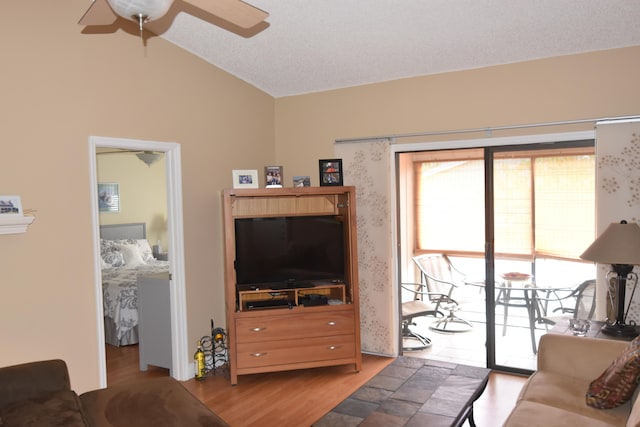 living room with a textured ceiling, hardwood / wood-style floors, ceiling fan, and vaulted ceiling