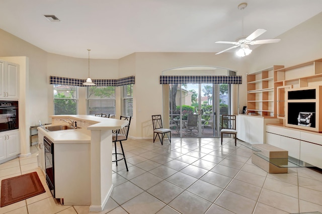 kitchen featuring a kitchen island with sink, black appliances, pendant lighting, light tile patterned floors, and white cabinetry