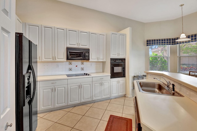 kitchen featuring black appliances, light tile patterned flooring, sink, hanging light fixtures, and white cabinetry