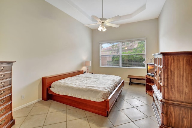 tiled bedroom featuring ceiling fan and a raised ceiling