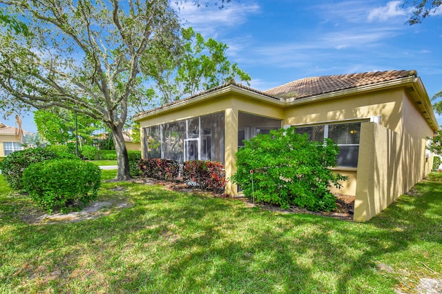 view of property exterior featuring a sunroom and a lawn