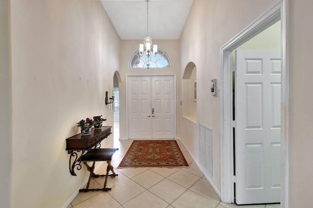 entrance foyer with a chandelier, light tile patterned flooring, and a high ceiling