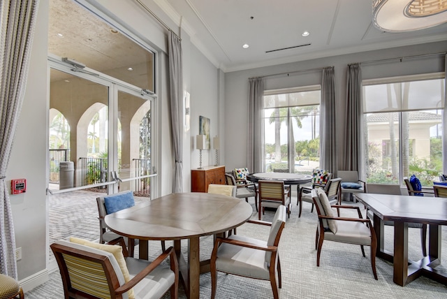 dining area with light carpet, ornamental molding, and a healthy amount of sunlight