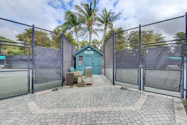 view of tennis court featuring a shed