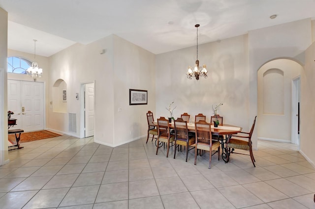 dining area featuring light tile patterned flooring, a high ceiling, and an inviting chandelier