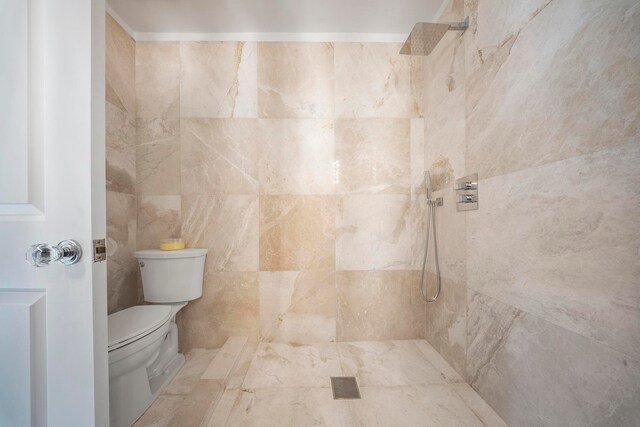 bathroom with a tile shower, tile walls, and toilet