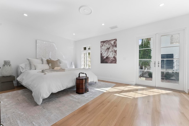 unfurnished bedroom featuring multiple windows, french doors, light wood-type flooring, and access to exterior