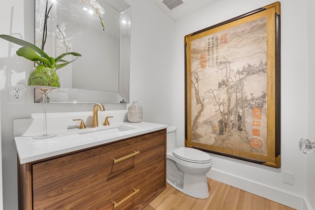 bathroom with toilet, vanity, and hardwood / wood-style flooring