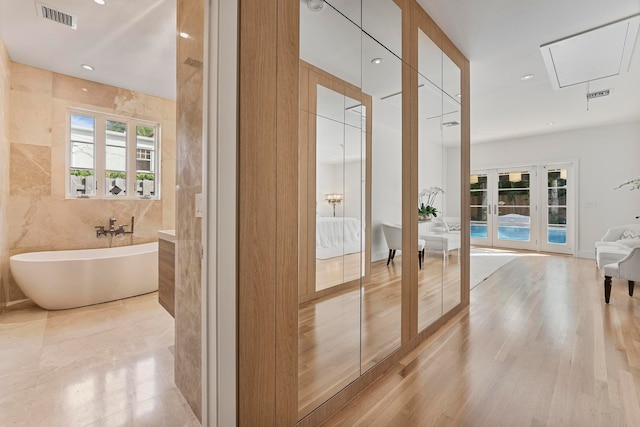 hall with french doors, tile walls, and hardwood / wood-style flooring