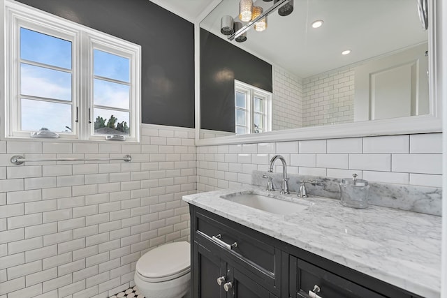 bathroom featuring vanity, toilet, and tile walls