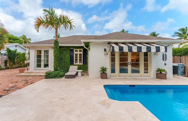 rear view of property featuring french doors, a patio, and a fenced in pool