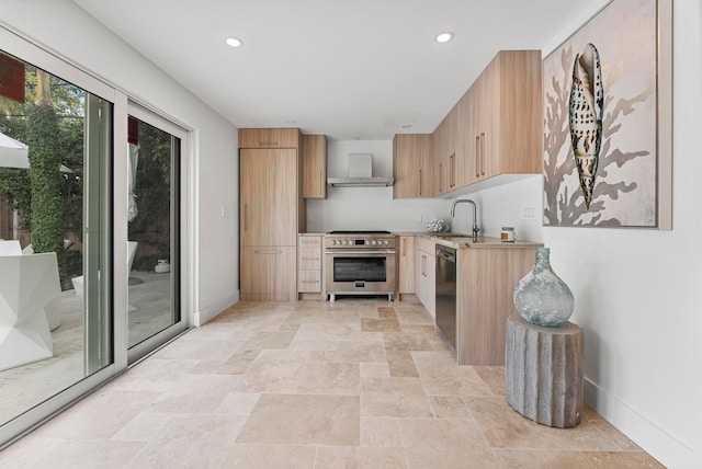 kitchen featuring high end stainless steel range oven, sink, wall chimney range hood, light brown cabinets, and dishwasher