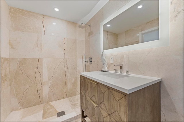 bathroom featuring vanity, tiled shower, and tile walls