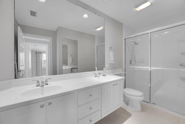 bathroom with a shower with door, vanity, toilet, and tile patterned flooring