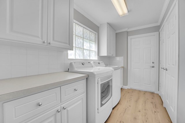 washroom with ornamental molding, light hardwood / wood-style flooring, separate washer and dryer, and cabinets