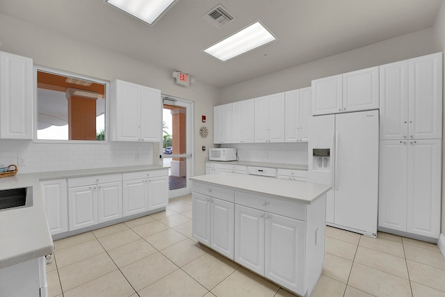 kitchen featuring white appliances, light tile patterned flooring, and white cabinets