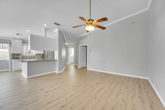 unfurnished living room with light hardwood / wood-style floors, crown molding, a textured ceiling, and vaulted ceiling