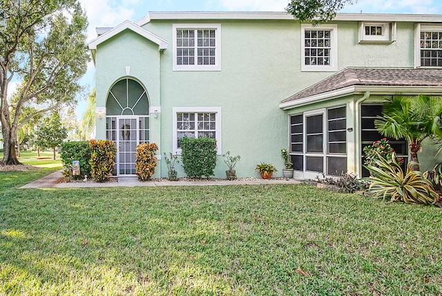 back of property with a lawn and a sunroom