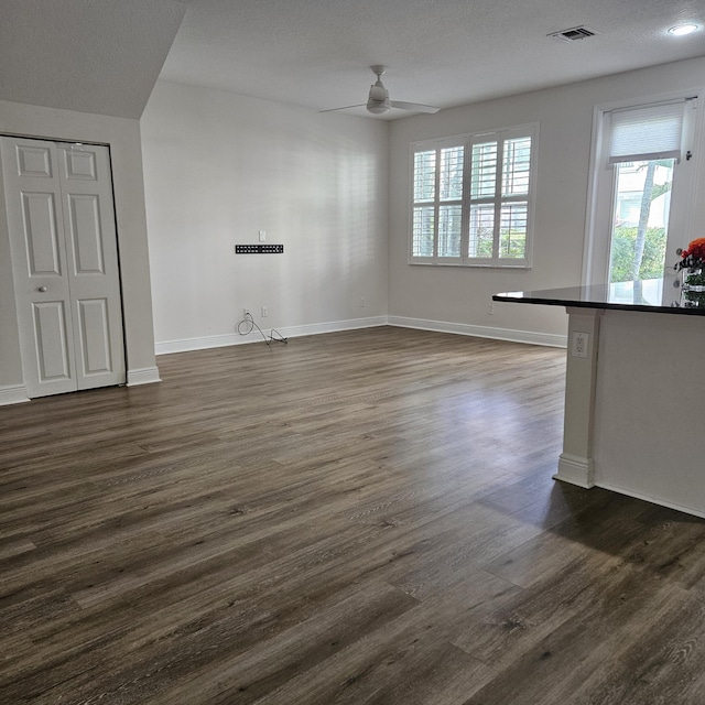 unfurnished living room featuring dark wood-style floors, visible vents, ceiling fan, and baseboards