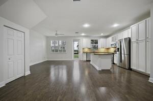 kitchen featuring dark wood-style floors, stainless steel refrigerator with ice dispenser, a kitchen island, and white cabinets