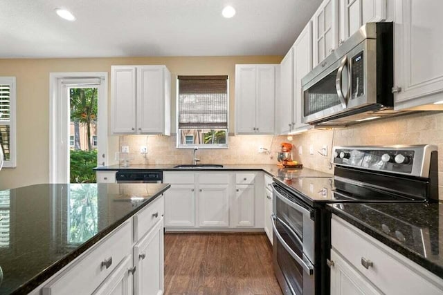 kitchen with dark wood-type flooring, a sink, white cabinetry, appliances with stainless steel finishes, and dark stone countertops