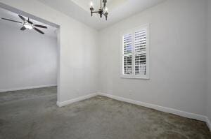 unfurnished dining area featuring ceiling fan with notable chandelier and baseboards