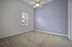 carpeted spare room with ceiling fan and baseboards