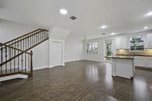 kitchen featuring dark wood-style floors, dark countertops, visible vents, open floor plan, and white cabinetry