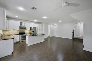 kitchen with stainless steel appliances, a sink, white cabinetry, a center island, and dark countertops