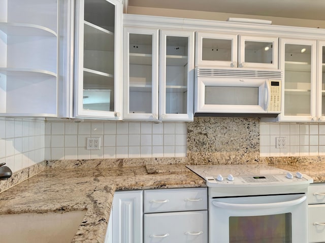 kitchen with white appliances, tasteful backsplash, sink, white cabinetry, and light stone counters