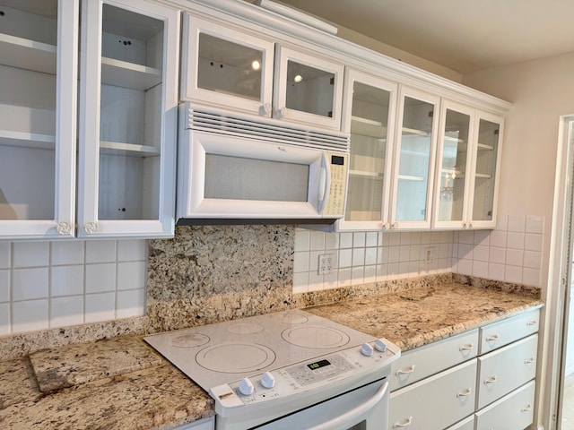 kitchen with white cabinetry, tasteful backsplash, stove, and light stone countertops