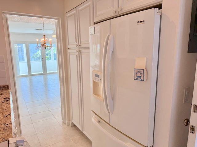 kitchen featuring light stone counters, light tile patterned flooring, white refrigerator with ice dispenser, and white cabinetry