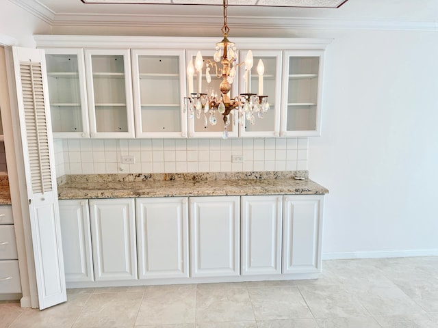 interior space featuring a chandelier, white cabinets, and backsplash