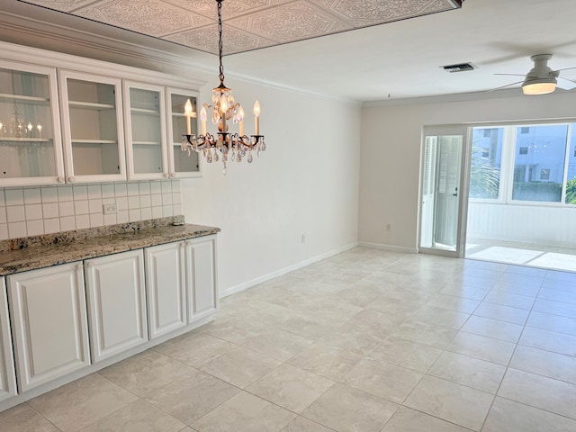 unfurnished dining area with ornamental molding, light tile patterned floors, and ceiling fan with notable chandelier