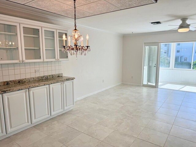 interior space with ornamental molding, white cabinetry, decorative light fixtures, and backsplash