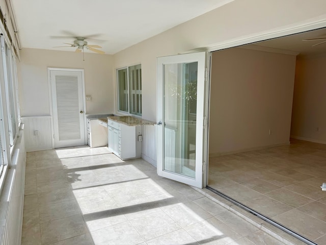 unfurnished sunroom featuring ceiling fan