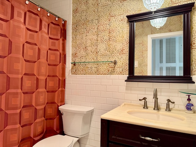 bathroom featuring toilet, vanity, and tile walls