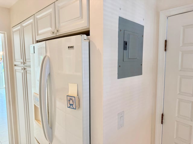 interior space with electric panel and white refrigerator with ice dispenser