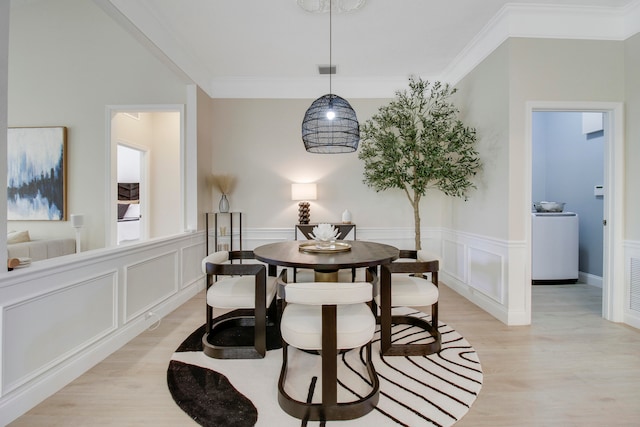 dining room with washer / dryer, crown molding, and light hardwood / wood-style floors