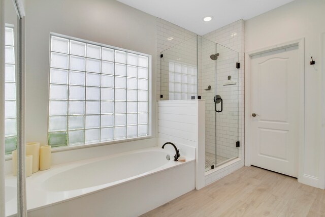 bathroom with a wealth of natural light, shower with separate bathtub, and wood-type flooring