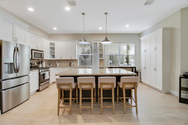 kitchen featuring a center island, decorative backsplash, light stone countertops, and stainless steel appliances